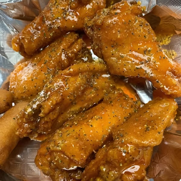 Close-up of Late Night Eats' honey-glazed chicken wings with seasoning, served in a plastic container.