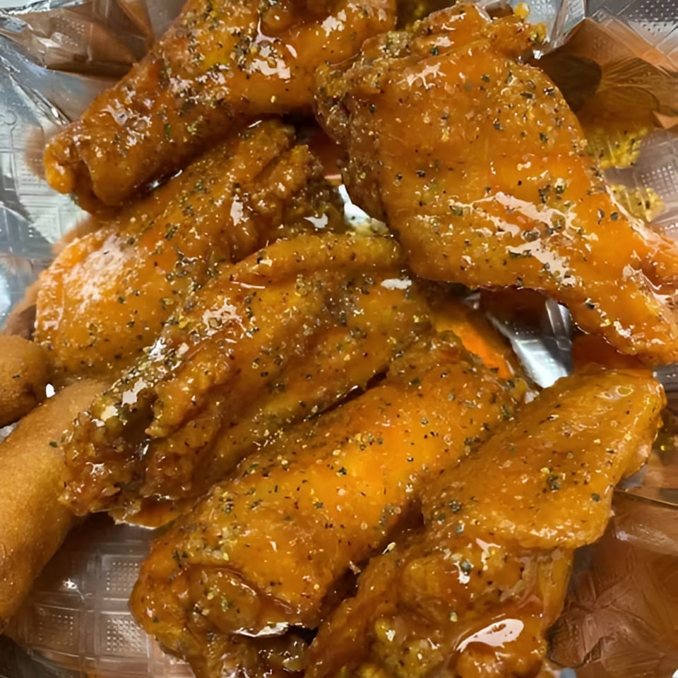 Close-up of Late Night Eats' honey-glazed chicken wings with seasoning, served in a plastic container.