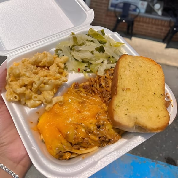 Soul food takeout with mac and cheese, cabbage, baked spaghetti, and garlic bread.
